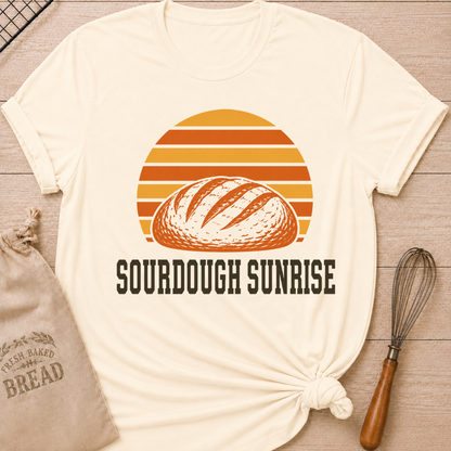 Natural women's relaxed fit t-shirt with a hand-scored sourdough loaf and a bold retro sunrise in rich harvest colors.