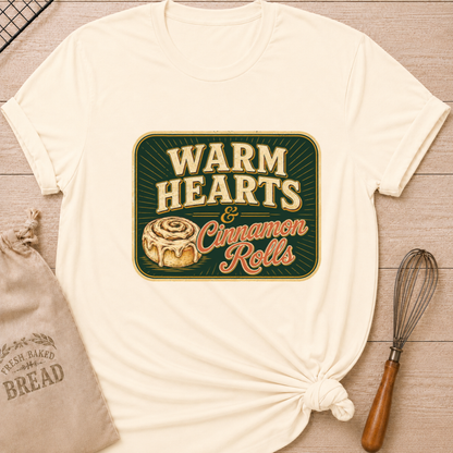 Natural women's relaxed fit t-shirt with the words Warm Hearts & Cinnamon Rolls in bold vintage lettering with a gooey iced cinnamon roll in a retro sign style.