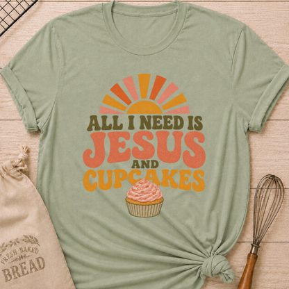 Sage All I Need Is Jesus and Cupcakes women's relaxed fit tee with retro lettering and a pink frosted cupcake in warm sunrise colors