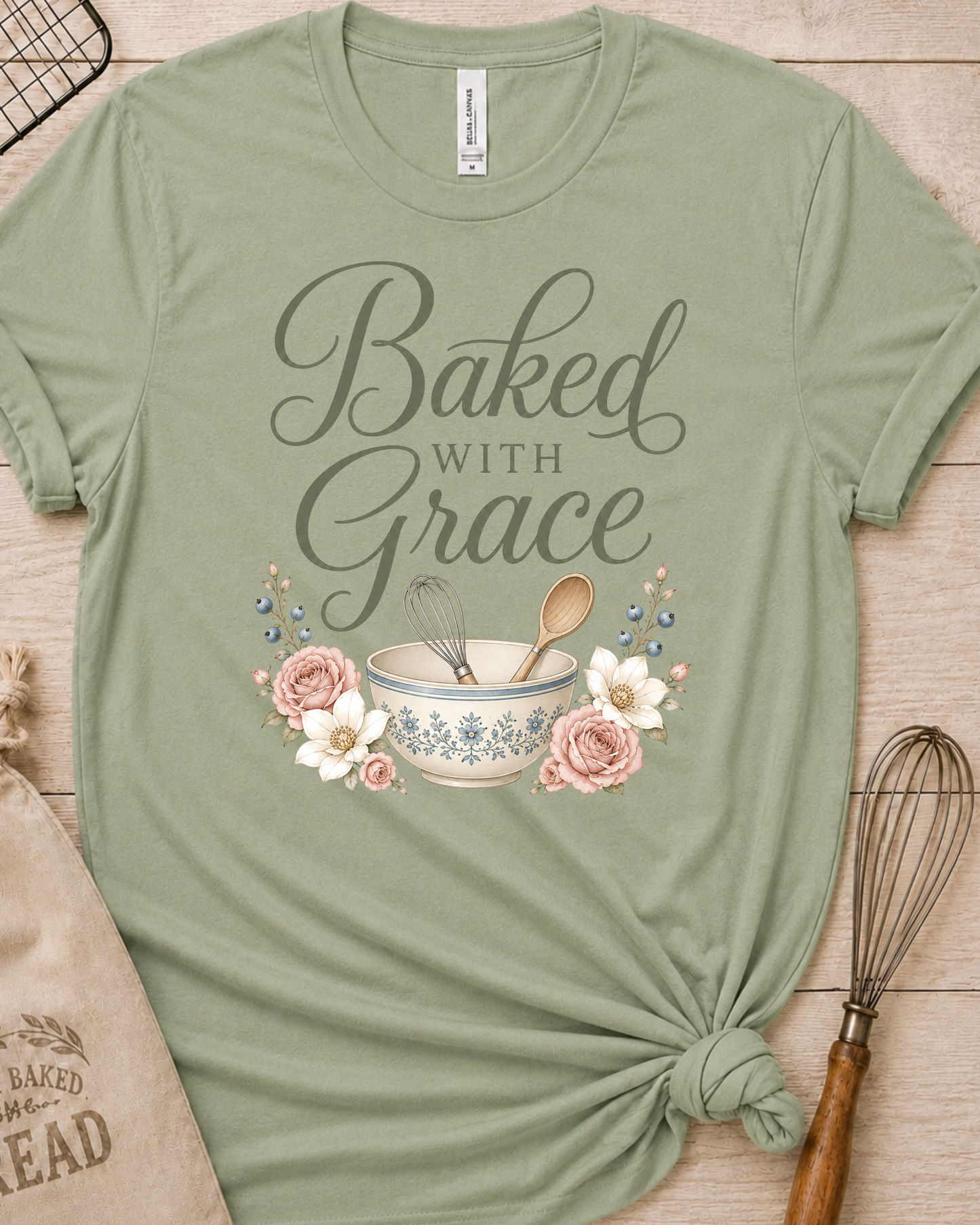 Sage green women's relaxed fit t-shirt with Baked with Grace in script surrounded by soft blue watercolor florals.