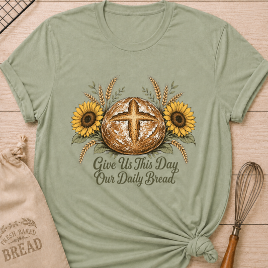 Sage green women's relaxed fit tee with a rustic sourdough loaf, golden wheat, and yellow sunflowers, reading Give Us This Day Our Daily Bread