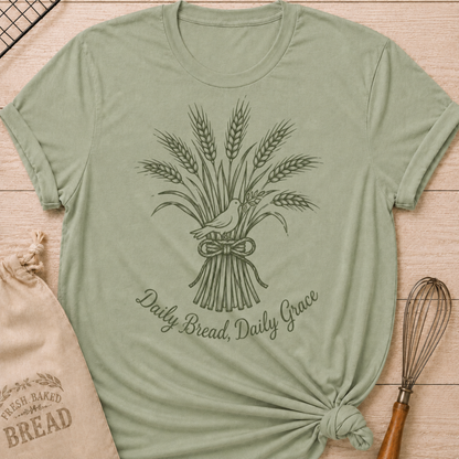Sage green women's relaxed fit t-shirt with a tied bundle of wheat and a dove and the words Daily Bread, Daily Grace.