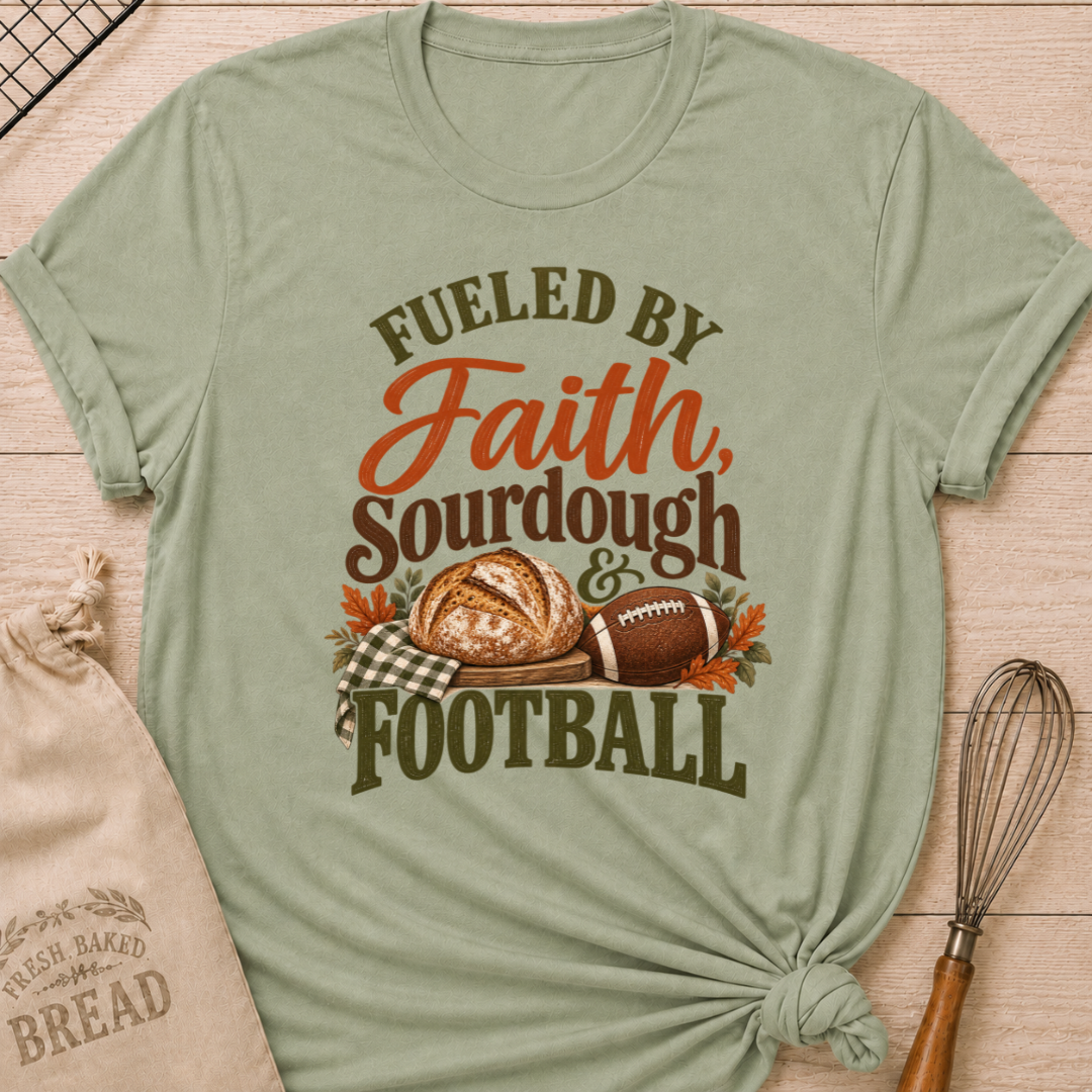 Sage women's relaxed fit tee with bold vintage Fueled by Faith Sourdough and Football lettering, a rustic sourdough loaf, classic football, gingham accents and autumn leaves