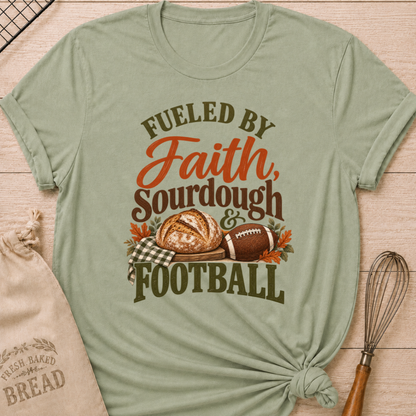 Sage women's relaxed fit tee with bold vintage Fueled by Faith Sourdough and Football lettering, a rustic sourdough loaf, classic football, gingham accents and autumn leaves