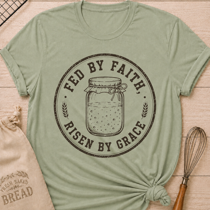 Sage green women's relaxed fit t-shirt with a vintage sourdough starter jar, wheat and the words Fed by Faith, Risen by Grace.