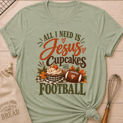 Sage women's relaxed fit tee with bold vintage All I Need Is Jesus, Cupcakes and Football lettering, a pumpkin topped cupcake, autumn leaves and a football on a gingham blanket