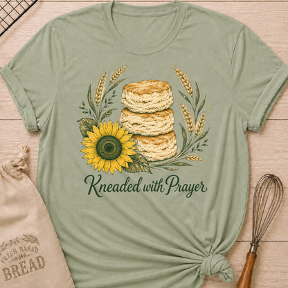 Sage Kneaded With Prayer women's relaxed fit tee with a stack of homemade biscuits, golden wheat, and a sunflower