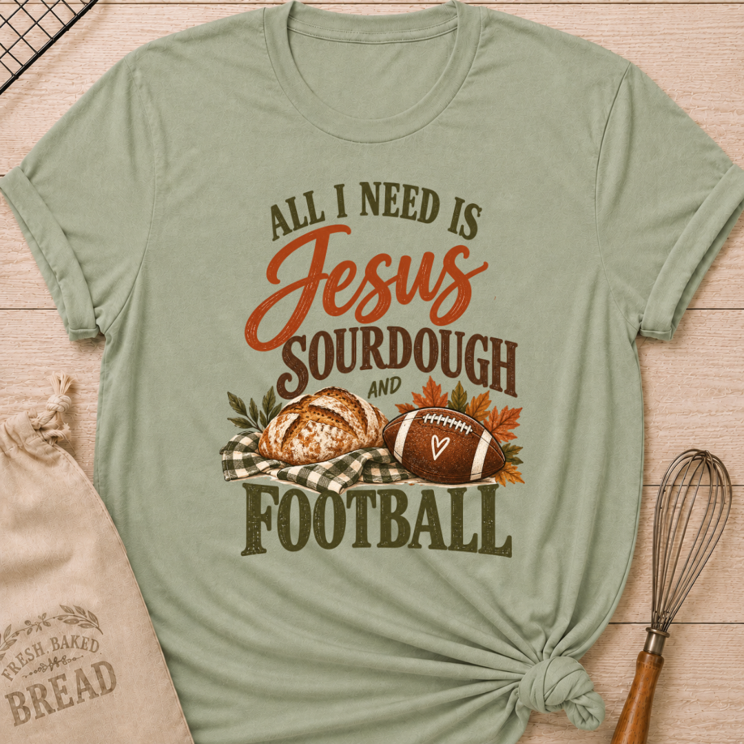 Sage women's relaxed fit tee with bold vintage All I Need Is Jesus, Sourdough and Football lettering, a rustic sourdough loaf, classic football, gingham accents and autumn leaves in rich harvest tones