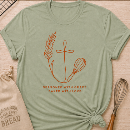 Sage green women's relaxed fit t-shirt with the words Seasoned With Grace, Baked With Love in clean line art with wheat, a subtle cross, and a classic whisk.