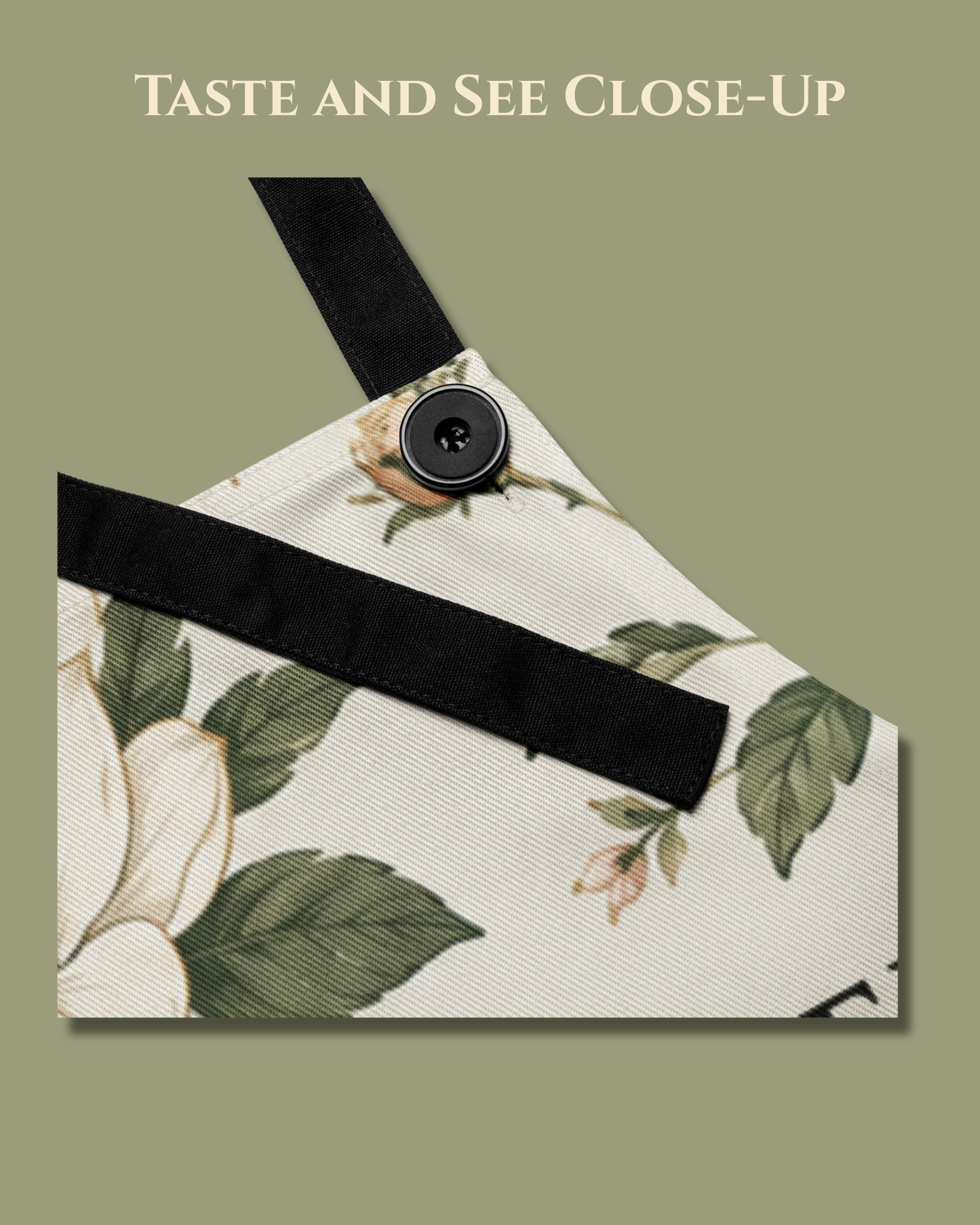 Close-up of the Taste and See apron showing the black adjustable neck strap and button detail against the cream floral fabric.
