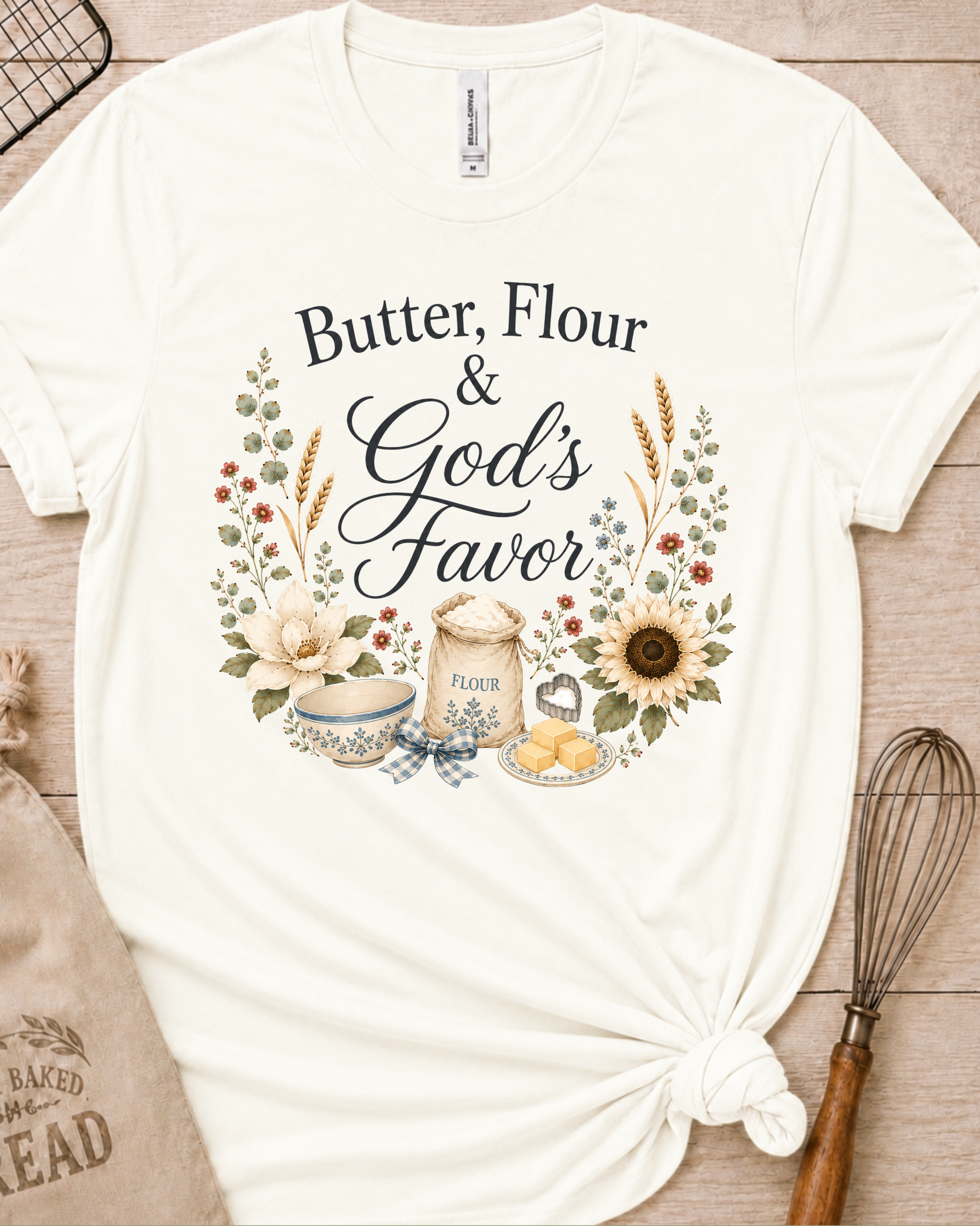 Vintage white women's relaxed fit t-shirt reading Butter, Flour and God's Favor, framed by a flour sack, a mixing bowl, butter, a sunflower, and wildflowers.
