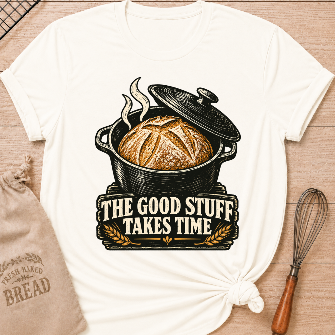 Vintage White women's relaxed fit tee with a golden artisan loaf rising from a vintage Dutch oven, steam curling overhead and wheat accents below, with The Good Stuff Takes Time lettering