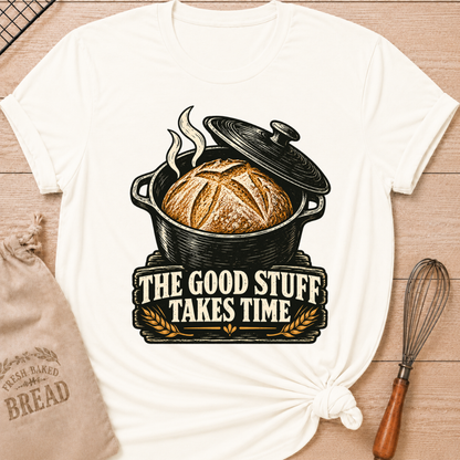 Vintage White women's relaxed fit tee with a golden artisan loaf rising from a vintage Dutch oven, steam curling overhead and wheat accents below, with The Good Stuff Takes Time lettering