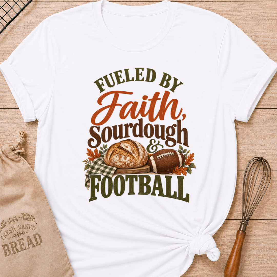 White women's relaxed fit tee with bold vintage Fueled by Faith Sourdough and Football lettering, a rustic sourdough loaf, classic football, gingham accents and autumn leaves