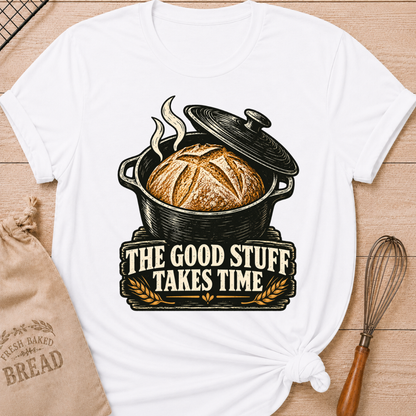 White women's relaxed fit tee with a golden artisan loaf rising from a vintage Dutch oven, steam curling overhead and wheat accents below, with The Good Stuff Takes Time lettering