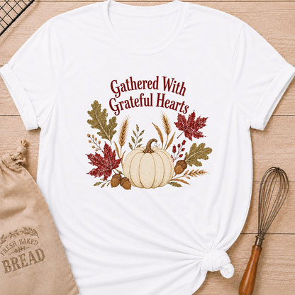 White women's relaxed fit tee with Gathered With Grateful Hearts lettering above a soft ivory pumpkin surrounded by wheat, acorns, berries and richly colored autumn leaves