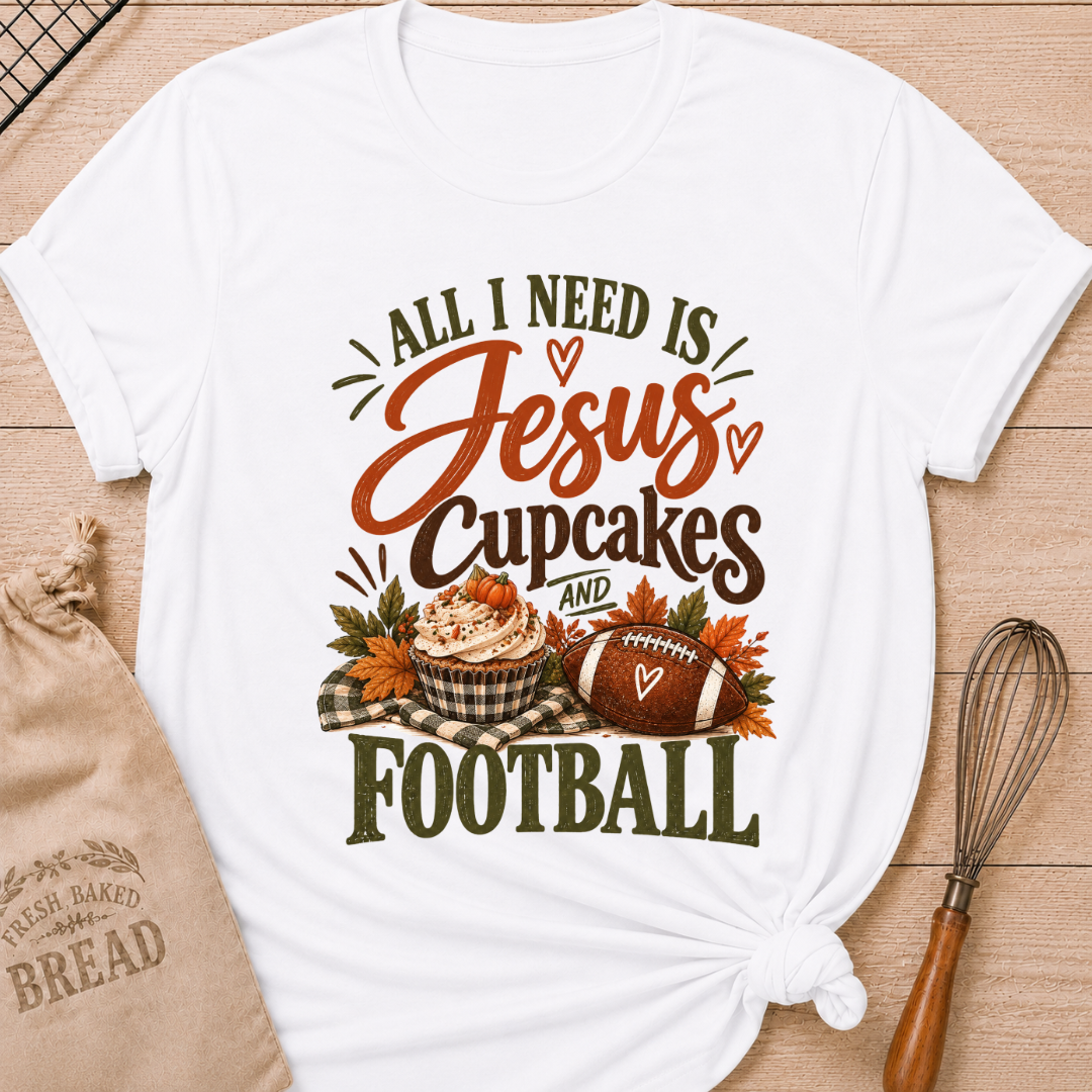 White women's relaxed fit tee with bold vintage All I Need Is Jesus, Cupcakes and Football lettering, a pumpkin topped cupcake, autumn leaves and a football on a gingham blanket